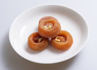 Poster - Close-up of stacked four Gotgam(Dried Persimmon) with pine nut seeds on white dish, South Korea
