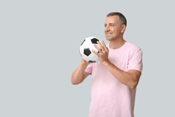 Wall Mural - Handsome mature man playing with soccer ball on grey background