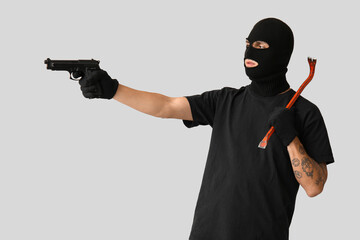 Poster - Male thief with crowbar and gun on grey background