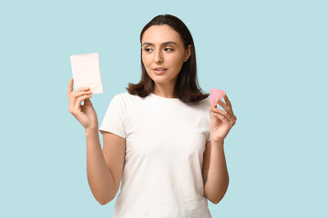 Sticker - Beautiful young woman with menstrual cup and pad on blue background