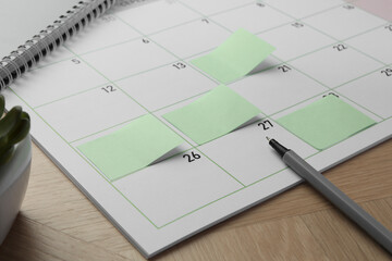 Wall Mural - Timetable. Calendar page with green sticky notes and pen on wooden table, closeup