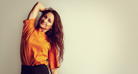 Wall Mural - Beautiful relaxing happy casual woman in bright orange t-shirt looking on blue studio background on empty copy space. Closeup