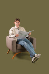 Handsome young man reading newspaper and sitting in armchair on green background