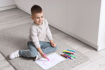 Sticker - Cute little boy drawing with felt-tip pens on floor in kitchen