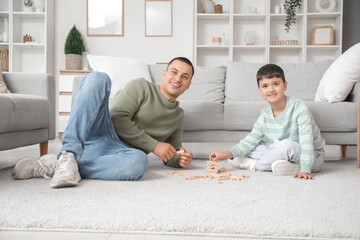 Wall Mural - Cute little boy with his father playing jenga game at home