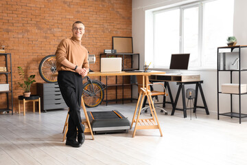 Wall Mural - Young businessman near treadmill in office