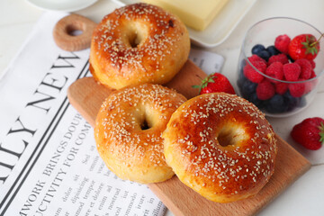 Wall Mural - Board with tasty bagels and berries on white wooden background