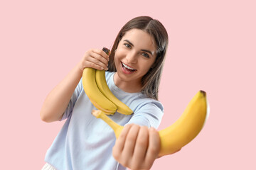 Wall Mural - Young woman with bananas on pink background