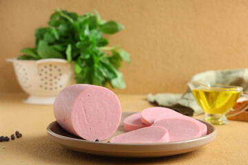 Wall Mural - Plate with slices of tasty boiled sausage, basil and oil on beige background