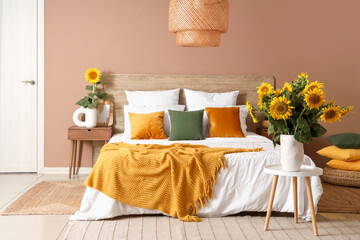 Poster - Stylish bedroom with big bed and vases of sunflowers bouquets on stool