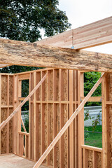 Wall Mural - Closeup detail of new house construction, large glue laminate wood support beam crossing a Parallel Strand Lumber support beam, building framing started with walls and windows
