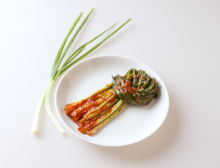 Poster - Close-up of Pagimchi(green onion kimchi) with seasoning on a dish and two trimmed fresh stem and leaf, South Korea
