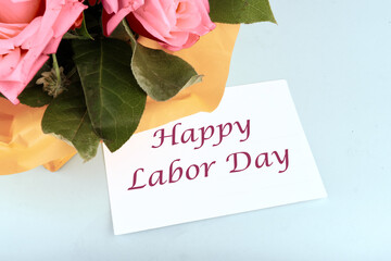 Happy Labor Day Text on a white business card on a blue background in a composition with a bouquet of flowers