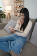 © snowing12 - Young asian women reading a book to studying and thinking about knowledge educational while sitting on the couch to learning self-study and spending time to relaxation with enjoying lifestyle at home