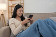 © snowing12 - Young asian women typing message chat on smartphone and watching movie entertainment to laughing with happiness while lying on couch to spending time and relaxation with enjoying lifestyle at home