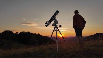 Wall Mural - Amateur astronomer looking at the evening skies, observing planets, stars, Moon and other celestial objects with a telescope just before sun down.