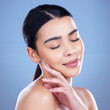 © peopleimages.com - Skincare, beauty and face of woman on blue background for cosmetics, wellness and skincare. Dermatology, health and person touch for satisfaction with natural skin, salon and facial care in studio