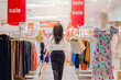 © shine - Woman with many shopping bags walking down the hallway of a mall after buying shoes and clothes on sale. Sale tag of offering special promotion hanging in mall. Mannequins in flower pattern dress.