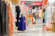 © shine - Asian woman holding many shopping bags, feels happy buying new clothes in shopping mall, Choosing stylish clothes, Colorful brand designs. A row of variety clothes hanging on rack. Store discount sign