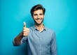 © kansak01 - Young man standing over isolated blue background doing happy thumbs up gesture with hand.