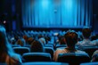 © AiHRG Design - An audience sits in a darkened theater, captivated by a performance on stage, with soft blue lighting highlighting their silhouettes.