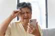 © Pormezz - Elderly woman have eyesight problem can not read because seeing text blurred and headache from eye tired.