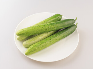 Poster - Close-up of four fresh cucumbers on white dish, South Korea
