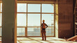 © VK Studio - A lone worker stands in a vast, empty room with large windows, bathed in sunlight, contemplating possibilities and planning ahead.