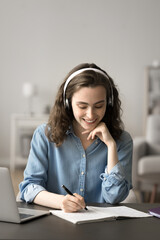 Canvas Print - Pretty young student woman sit at desk, wear headphones listen online audio lesson on laptop, working on school project, prepare for exams use modern wireless technology. Education, e-learning process