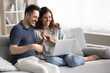 © fizkes - Happy wife and husband using laptop at home, make video call to family using application, watching on-line movie via digital streaming subscription services, enjoy pleasant pastime at home on internet