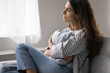 © fizkes - Pensive single woman sits on sofa, gazing out of window in deep contemplation, suffers from solitude, emotional distress, coping with personal troubles and break up, goes through difficult life period