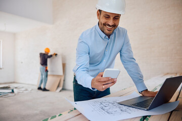happy architect using cell phone while working at construction site.