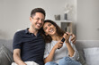 © fizkes - Romantic couple relaxing on cozy couch in living room watching television, enjoy favourite classic comedy movie via subscription-based streaming services. Weekend leisure, family hobby and pastime