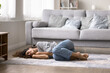 © fizkes - Young pretty woman fell asleep lying down on floor curled up in soft rug in cozy warm living room, relieving fatigue, relax alone at home, looks serene and peaceful. Exhaustion relief, rest, comfort