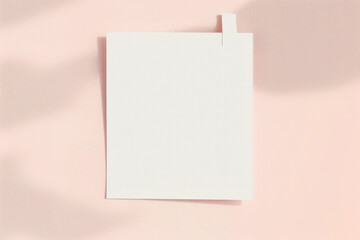 A blank white post-it note on a light pink background