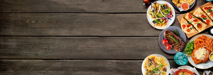 Leinwandbilder - Side border of various delicious foods. Overhead view on a dark wood banner background. Copy space. Pastas, flatbreads, tacos, steak and restaurant theme dishes.