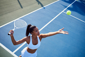 Sticker - Black woman, racket and playing tennis in outdoor, confident serve and sports workout on court. Female person, fitness and ball for game or match at club, exercise and energy for training practice