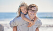 © Alex Shared/peopleimages.com - Dad, portrait and daughter for piggyback on beach, promenade and hug for support in outdoor. Father, girl and carrying game or embrace on vacation, bonding and holiday for seaside freedom by ocean