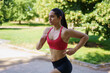 © javiindy - A woman is jogging in a park on a sunny day, dressed in sportswear, showcasing her dedication to an active lifestyle