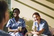 © Maskot - Smiling female medical workers holding coffee glasses and talking with colleague at hospital