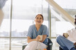 © Maskot - Smiling female medical expert holding disposable cup while sitting with colleague in cafeteria