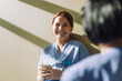 © Maskot - Smiling female medical trainee holding disposable cup near wall at hospital