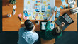 © Summit Art Creations - Top view of smart manager working together to develop Ux Ui design for mobile interface. Developer partner working together discussing about changing software app while using on laptop. Convocation.