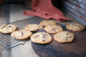 Chocolate chunk cookies cooling on a black wire cooling rack on a wooden tabletop.