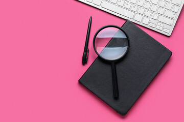 Notebook, pen, magnifier and keyboard on pink background. World Poetry Day celebration