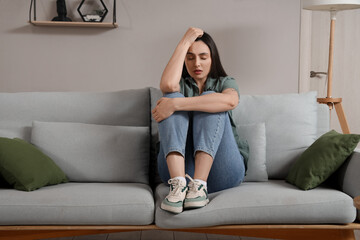 Sticker - Depressed young woman sitting on sofa at home