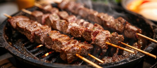 Aufkleber - Meat skewers with beef cooking on a sizzling black iron pan embodying a street food theme Perfect for adding copy space image