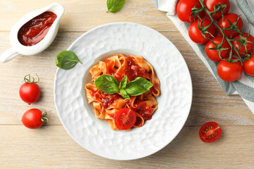 Wall Mural - Delicious pasta with sauce, tomato and basil on wooden table, flat lay