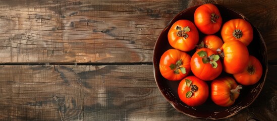 Leinwandbilder - Bowl of autumn persimmons on wooden table backdrop with dark rustic style ideal for a natural remedy Includes copy space image