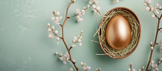 Poster - Easter themed card displaying a golden egg in a tray with delicate willow branches on a soft green background allowing room for text Ideal for Easter greetings Top down view. with copy space image